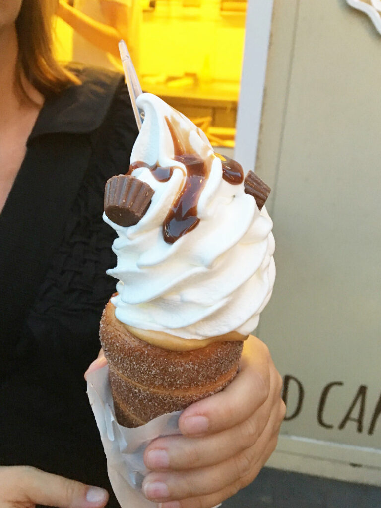 Ein spiralförmiges, mit Zucker und Zimt bestäubtes Baumstriezel-Hörnchen (Trdelník) von Sweet Krakau, gefüllt mit weißem Softeis, Erdnussbutter, Schokoladensauce und kleinen Erdnussbutter-Pralinen.