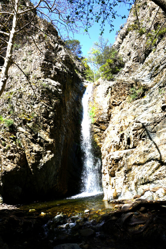 Ein schmaler Wasserfall stürzt zwischen steilen, zerklüfteten Felswänden in ein flaches Becken und bietet ein Beispiel für naturnahe Ausflüge in der Umgebung von Barcelona.