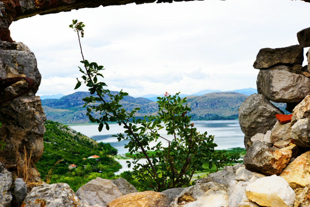Blick durch eine steinerne Maueröffnung einer Festung auf den Skadarsee in Montenegro,