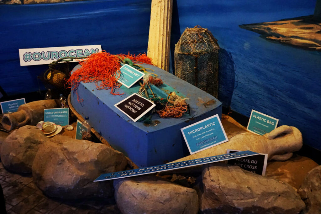 Eine Ausstellung im Malta National Aquarium zeigt Meeresmüll wie Fischernetze und Plastikflaschen neben antiken Amphoren, um auf die Plastikverschmutzung der Ozeane aufmerksam zu machen.