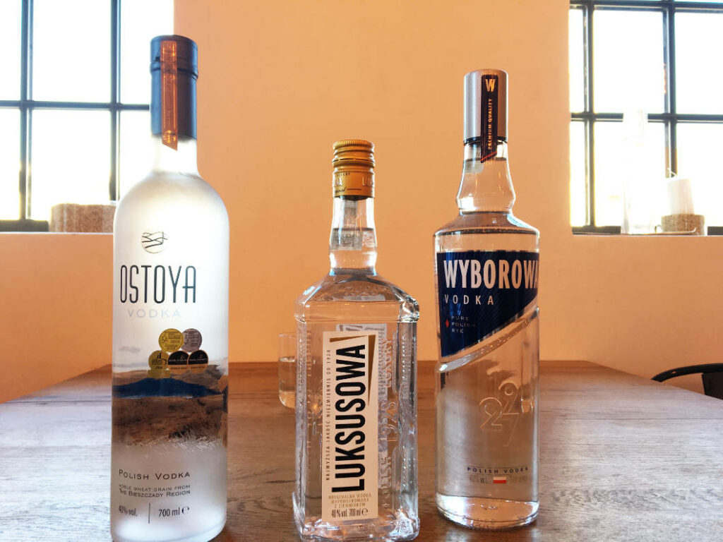 Drei verschiedene Flaschen polnischer Wodka der Marken Ostoya, Luksusowa und Wyborowa stehen nebeneinander auf einem Holztisch für ein Tasting im Polnischen Wodka Museum in Warschau.