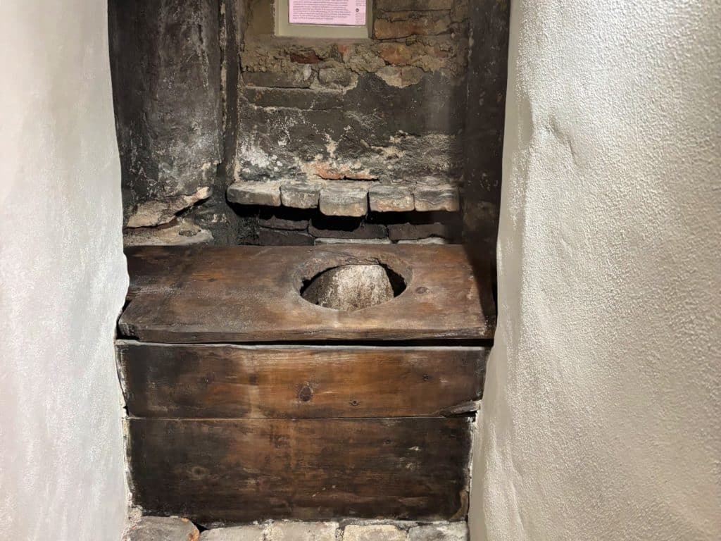 Ein historisches hölzernes Plumpsklo in einer engen Mauernische des Ethnografischen Museums der Region Pilsen in Tschechien.