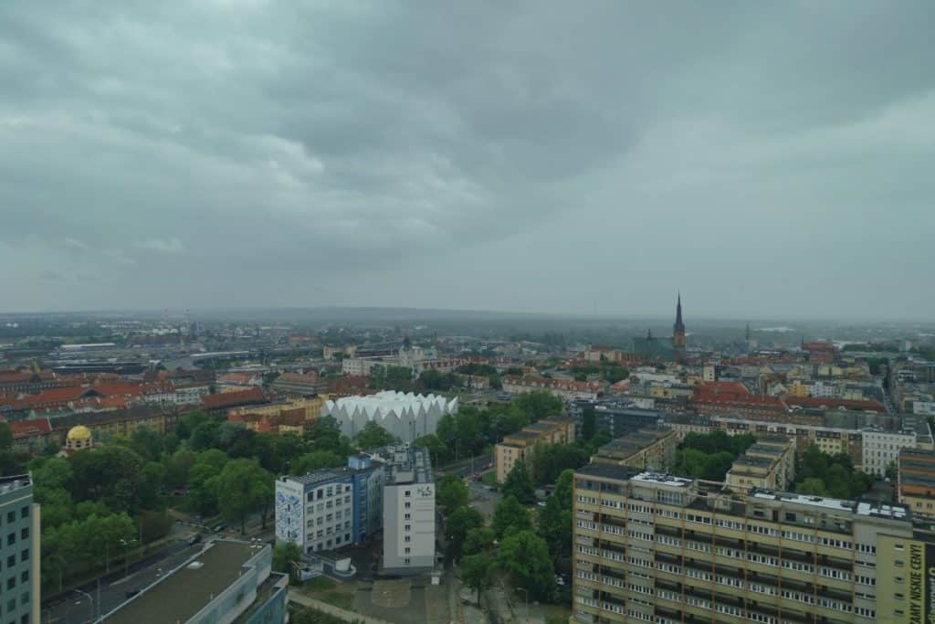 Blick aus dem Café 22 über die Dächer von Stettin auf die markante, weiße Architektur der Philharmonie und den Turm der Jakobskathedrale unter einem bewölkten Himmel.