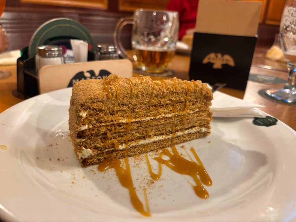 Ein Stück traditioneller tschechischer Honigkuchen, serviert auf einem weißen Teller mit Karamellsauce im Restaurant U Salzmannů in Pilsen.