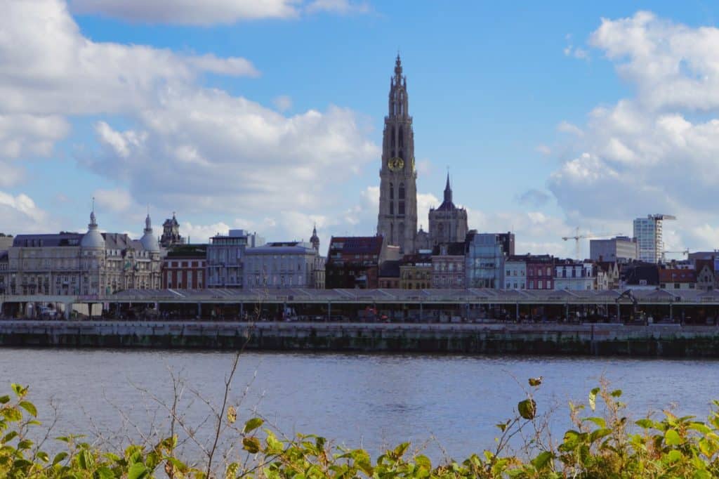 Blick über die Schelde auf die Skyline von Antwerpen mit der markanten Liebfrauenkathedrale, die über die umliegenden Gebäude und das Flussufer ragt.