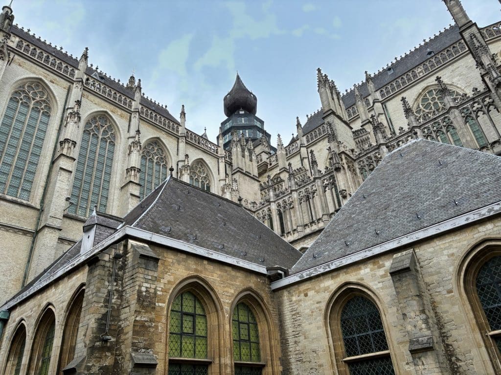 Außenansicht der Liebfrauenkathedrale in Antwerpen mit ihren gotischen Steinmetzarbeiten, hohen Spitzbogenfenstern und den charakteristischen Schieferdächern vor einem bewölkten Himmel.