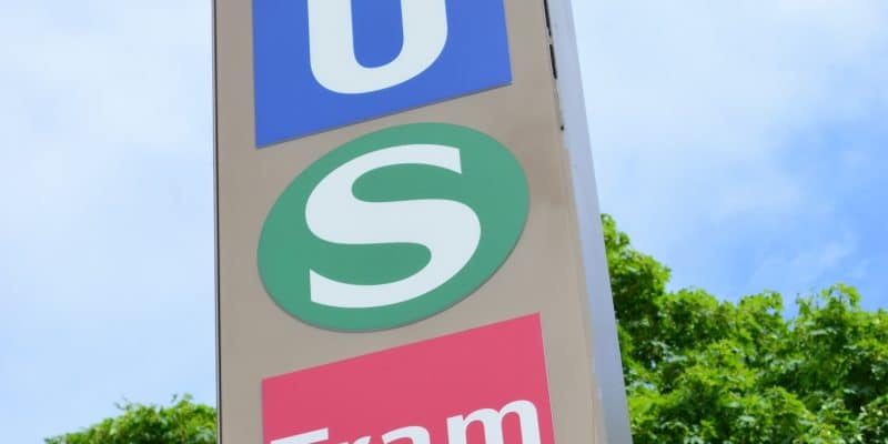 Ein Hinweisschild am Stachus in München zeigt untereinander die Symbole für die U-Bahn (weißes U auf blauem Grund), die S-Bahn (weißes S im grünen Kreis) und die Tram (weißer Schriftzug auf rotem Grund).