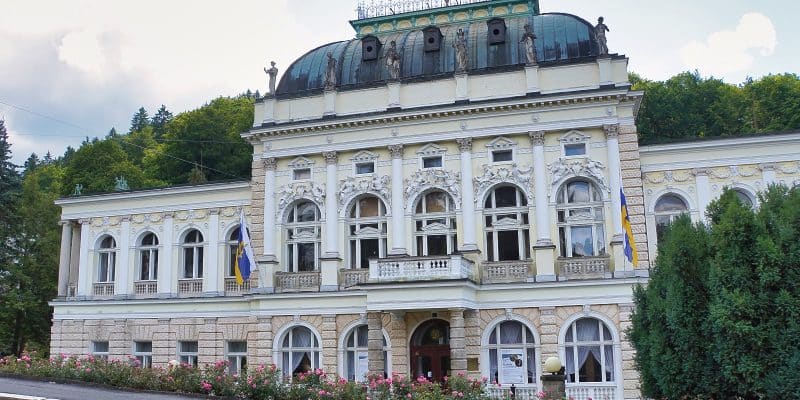 Außenansicht des neobarocken Casino in Marienbad mit einer kunstvollen Fassade, Statuen auf dem Dachgesims und einem gepflegten Rosengarten im Vordergrund.