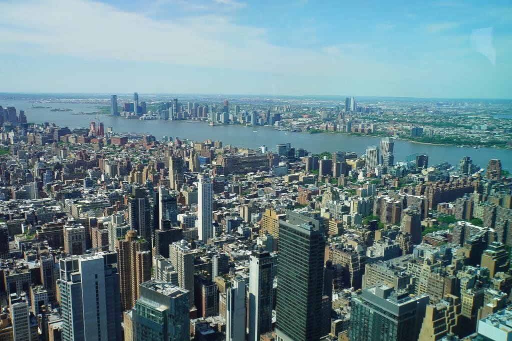 Weitläufige Panoramaansicht von New York City vom Empire State Building aus über die dichte Stadtbebauung bis hin zum Hudson River und der gegenüberliegenden Küste.