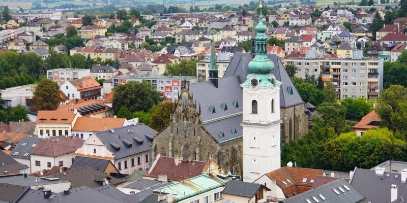 Blick über die Dächer von Klattau auf die Stadtpfarrkirche Mariä Geburt und den markanten Weißen Turm mit seiner grünen Zwiebelhaube vor einer hügeligen Landschaft.