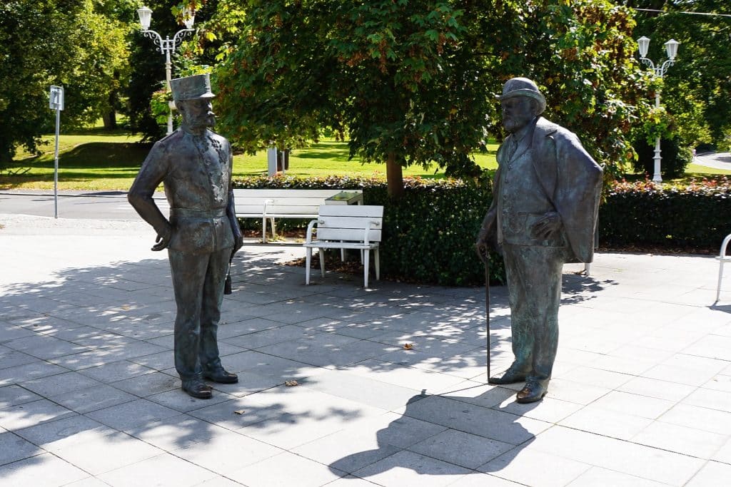 Sehenswürdigkeiten in Marienbad: Zwei lebensgroße Bronzestatuen des Herrscherdenkmals in Marienbad stellen Kaiser Franz Joseph I. in Uniform und König Edward VII. im Anzug bei einer Begegnung auf einem gepflasterten Platz dar.