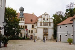 Blick auf den gepflasterten Innenhof und den Eingangsbereich des Hinterschlosses in Glauchau, Sachsen, mit seinem markanten Zwiebelturm und der historischen Fassade im Renaissancestil.
