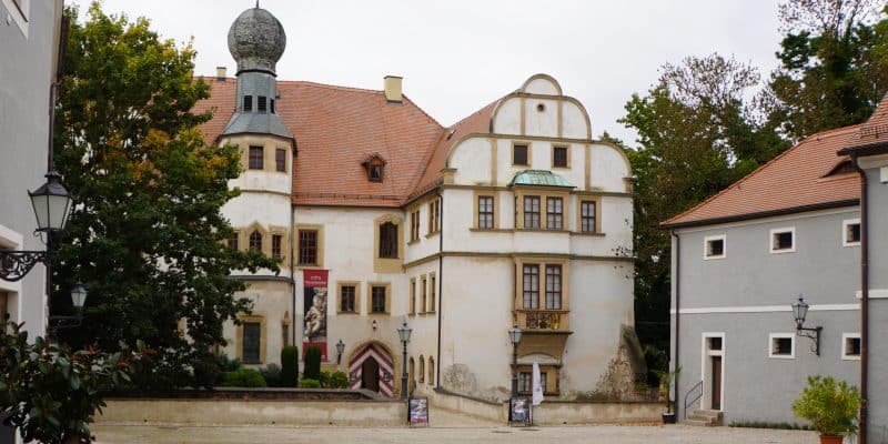 Blick auf den gepflasterten Innenhof und den Eingangsbereich des Hinterschlosses in Glauchau, Sachsen, mit seinem markanten Zwiebelturm und der historischen Fassade im Renaissancestil.