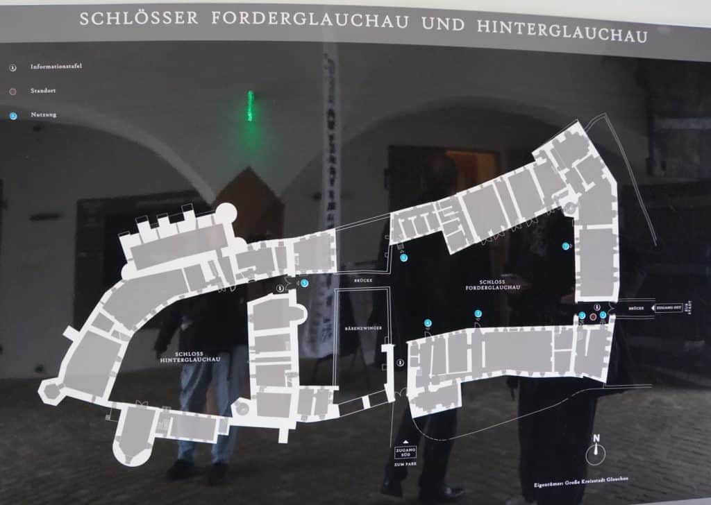 Ein schematischer Grundriss der Schlösser Forderglauchau und Hinterglauchau in Sachsen, der auf einer Informationstafel vor dem Hintergrund eines historischen Gewölbes abgebildet ist.