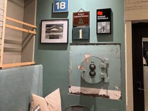 Eine grün gestrichene Wand in der Lobby des Hotels Trésor in Trois-Rivières ist mit historischen Bank-Erinnerungsstücken, einem Kalender vom 1. Januar und einem in die Wand eingelassenen, massiven alten Tresor dekoriert.