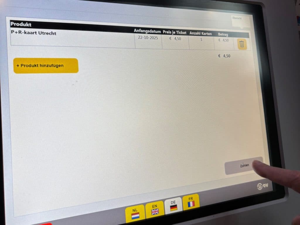 Ein Finger tippt auf den Button „Zahlen“ eines Ticketautomaten, auf dessen Bildschirm der Kauf einer P+R-Karte für Utrecht zum Preis von 4,50 Euro angezeigt wird.