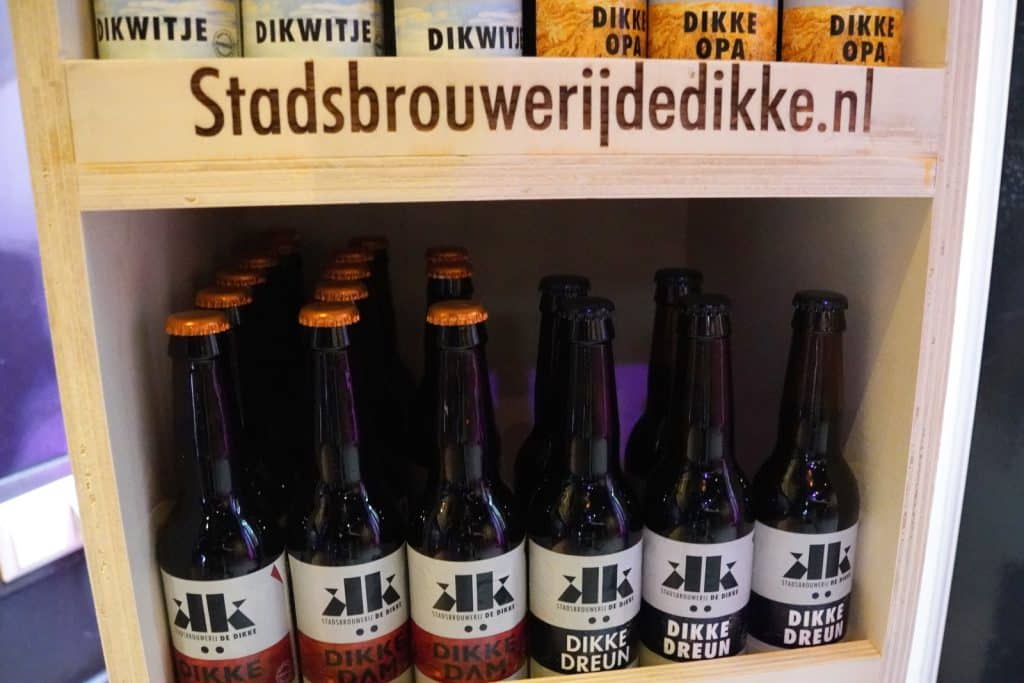 Ein Holzregal der Stadsbrouwerij de Dikke in Wijk bij Duurstede präsentiert verschiedene Bierflaschen, darunter die Sorten Dikke Dam und Dikke Dreun.