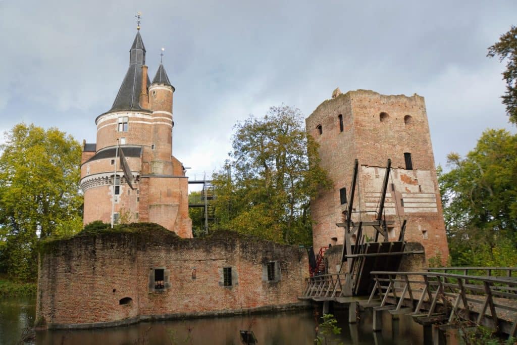 Die Ruinen der Wasserburg Wijk bij Duurstede mit einem gut erhaltenen runden Backsteinturm mit spitzem Dach, einem quadratischen Turmstumpf und einer hölzernen Zugbrücke über dem Wassergraben.