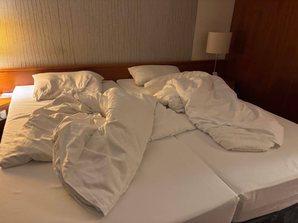 Ein ungemachtes Doppelbett mit zerwühlter weißer Bettwäsche in einem Zimmer des Maritim Airport Hotels Hannover.