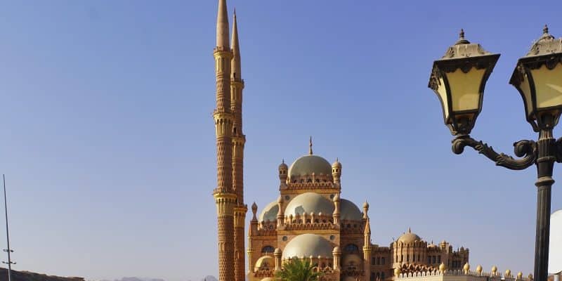 Die Al-Sahaba-Moschee in Sharm El Sheikh präsentiert sich mit ihrer kunstvollen Architektur aus sandfarbenem Stein, mehreren Kuppeln und zwei hoch aufragenden, schlanken Minaretten unter einem klaren blauen Himmel. Sharm El Sheikh Sehenswürdigkeiten