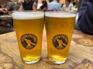 Zwei Gläser helles Bier mit weißer Schaumkrone stehen auf einem Holztisch in der Brauerei Le Temps d'une Pinte in Trois-Rivières.