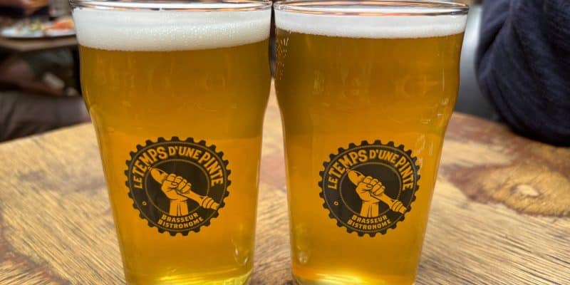 Zwei Gläser helles Bier mit weißer Schaumkrone stehen auf einem Holztisch in der Brauerei Le Temps d'une Pinte in Trois-Rivières.