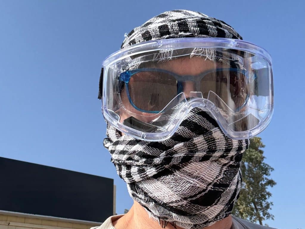 Nahaufnahme einer Person in Ägypten, die für eine Quad-Tour bereit ist und zum Schutz vor Sand ein schwarz-weiß gemustertes Tuch um Kopf und Gesicht sowie eine Schutzbrille über ihrer Sonnenbrille trägt.
