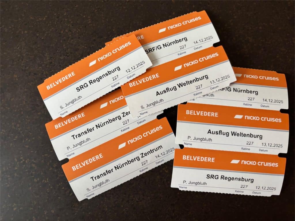 Mehrere orange-weiße Ausflugstickets für das Schiff Belvedere von nicko cruises, für verschiedene Ziele wie Regensburg, Weltenburg und Nürnberg im Dezember 2025.