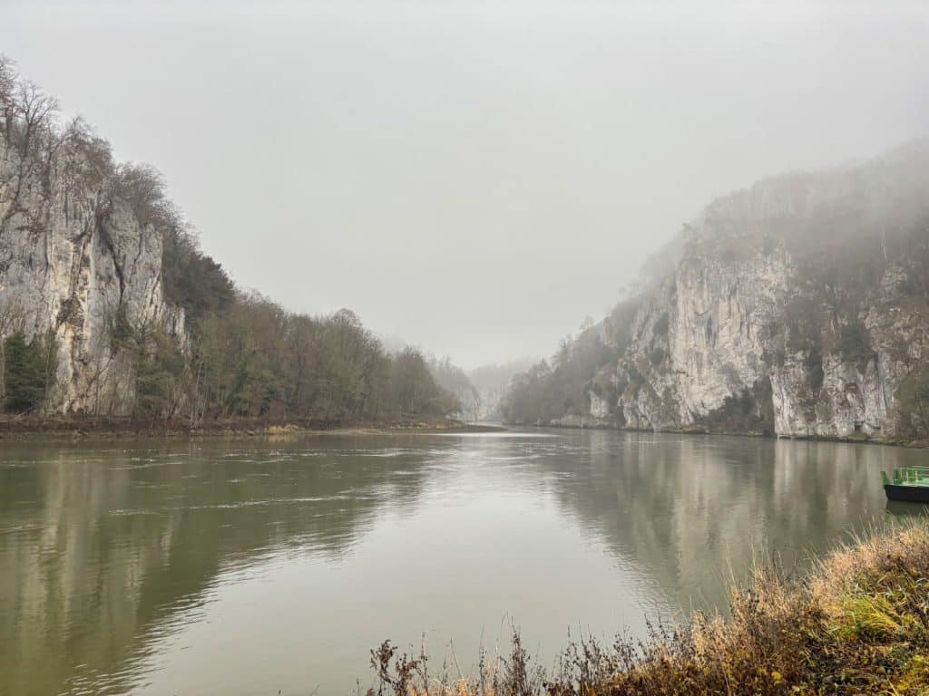 Blick auf den Donaudurchbruch bei Kelheim, wo der Fluss zwischen steilen, nebelverhangenen Kalksteinfelsen fließt.