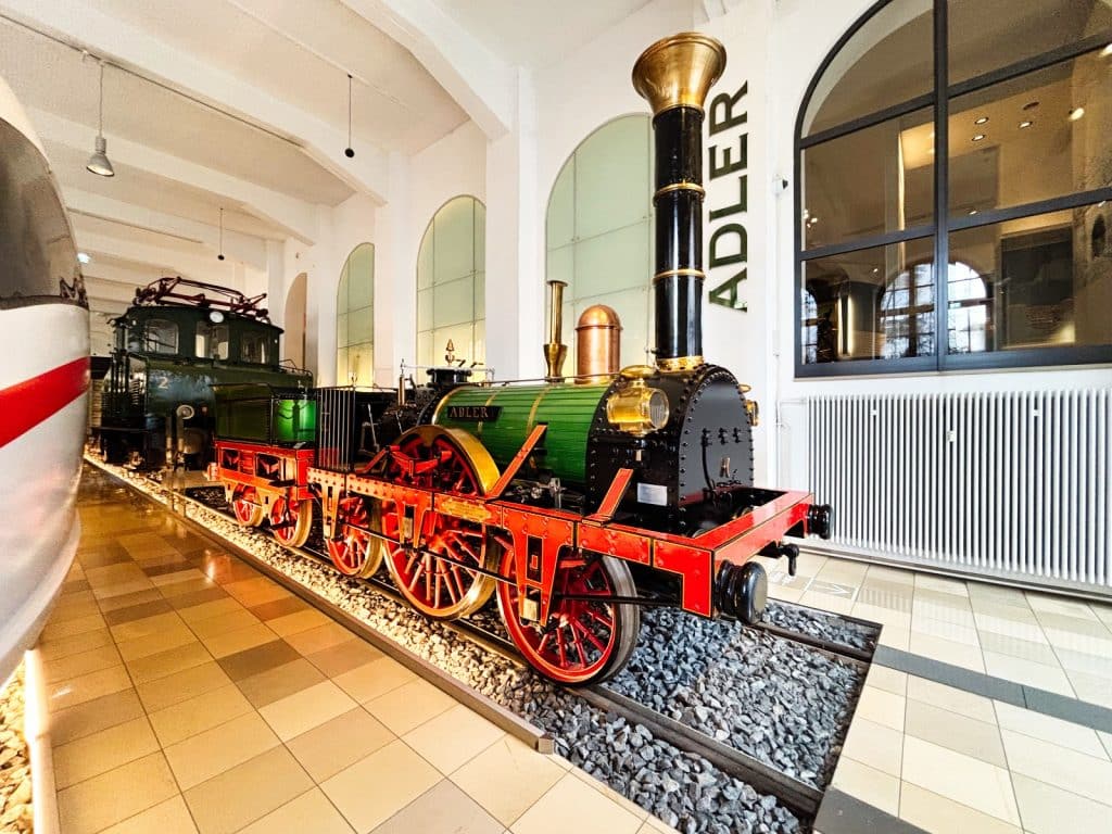 Eine detailgetreue Nachbildung der historischen Dampflokomotive „Adler“ steht auf einem Gleisbett im DB Museum in Nürnberg.