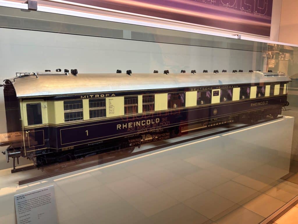 Ein detailliertes Modell eines historischen Rheingold-Speisewagens der Mitropa in den Farben Violett und Elfenbein.