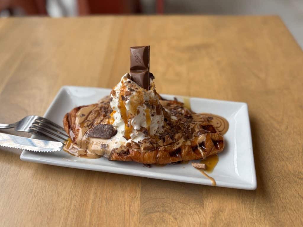 Ein mit Karamellsauce, Schokoladenstücken und Schlagsahne garniertes Croissant-Eis im Trois Rivières Eiscafé.