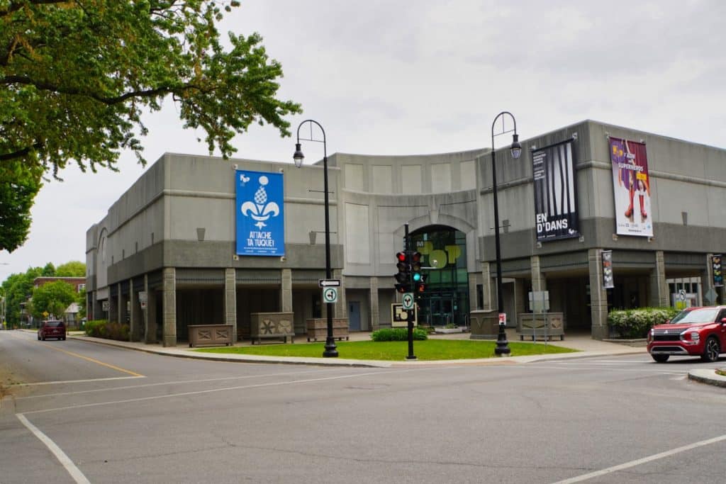Sehenswürdigkeiten in Trois-Rivières: Das Musée POP in Trois-Rivières präsentiert sich als modernes, graues Betongebäude an einer Straßenecke, geschmückt mit großen bunten Werbebannern für aktuelle Ausstellungen.