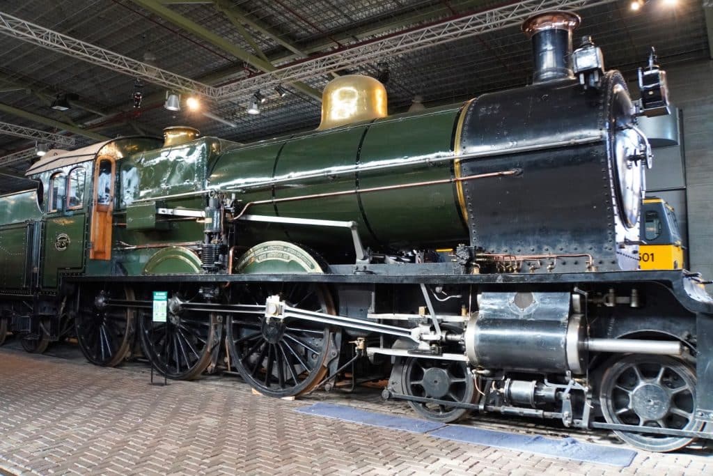 Eine große, dunkelgrüne Dampflokomotive mit goldenen Akzenten und schwarzen Rädern steht auf Schienen im Eisenbahnmuseum in Utrecht.