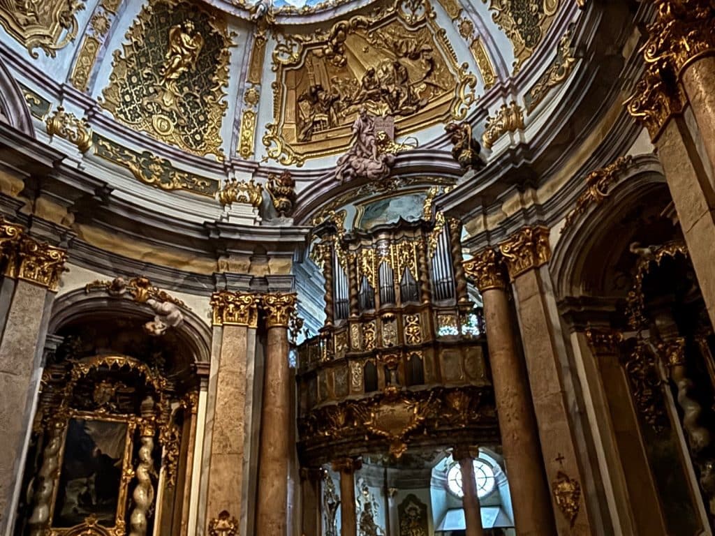 Blick in den prunkvollen, barocken Innenraum der Klosterkirche Weltenburg mit der reich verzierten Orgel unterhalb einer goldenen Kuppel mit Reliefs.