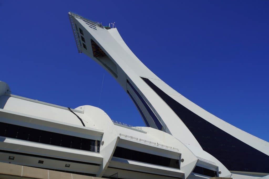 Olympische Spiele Montreal: Der weiße, geneigte Aussichtsturm des Olympiastadions in Montreal ragt vor einem strahlend blauen Himmel empor.