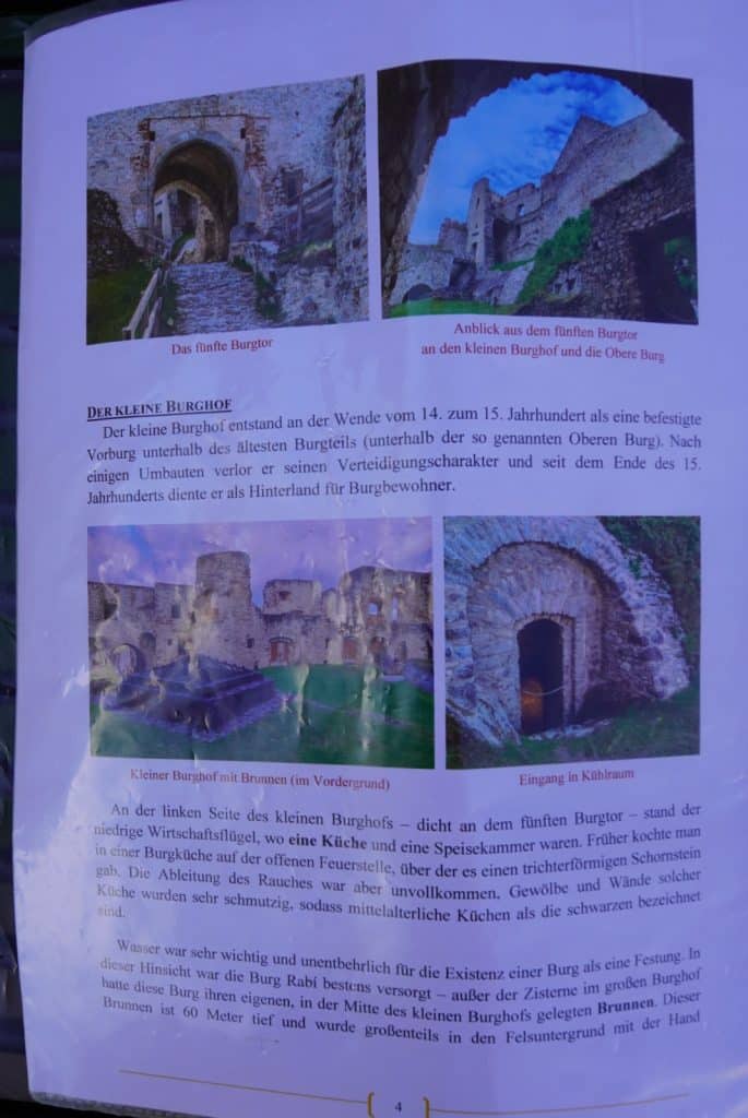 Eine Informationsseite zur deutschsprachigen Führung in der Burg Rabí zeigt vier Fotos der Ruine sowie begleitende Texte zum kleinen Burghof, der Burgküche und dem 60 Meter tiefen Brunnen. Die Bilder illustrieren das fünfte Burgtor, den Blick auf die obere Burg, den kleinen Burghof mit Brunnen sowie den Eingang zum Kühlraum.