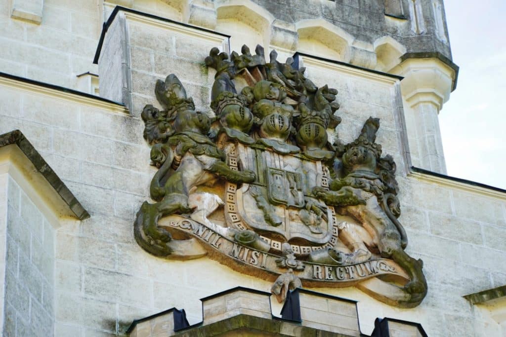Ein steinernes Wappen der Familie Schwarzenberg an der Fassade von Schloss Hluboká in Tschechien, flankiert von zwei Löwen und versehen mit dem lateinischen Wahlspruch „NIL NISI RECTUM“.