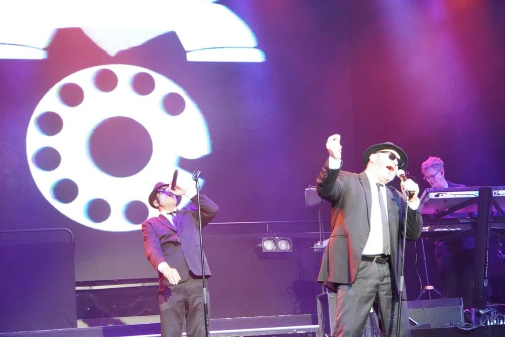 Zwei als Blues Brothers gekleidete Sänger treten bei der Show „Stars in Concert“ in Berlin auf einer Bühne vor einer großen Projektion einer Wählscheibe auf.
