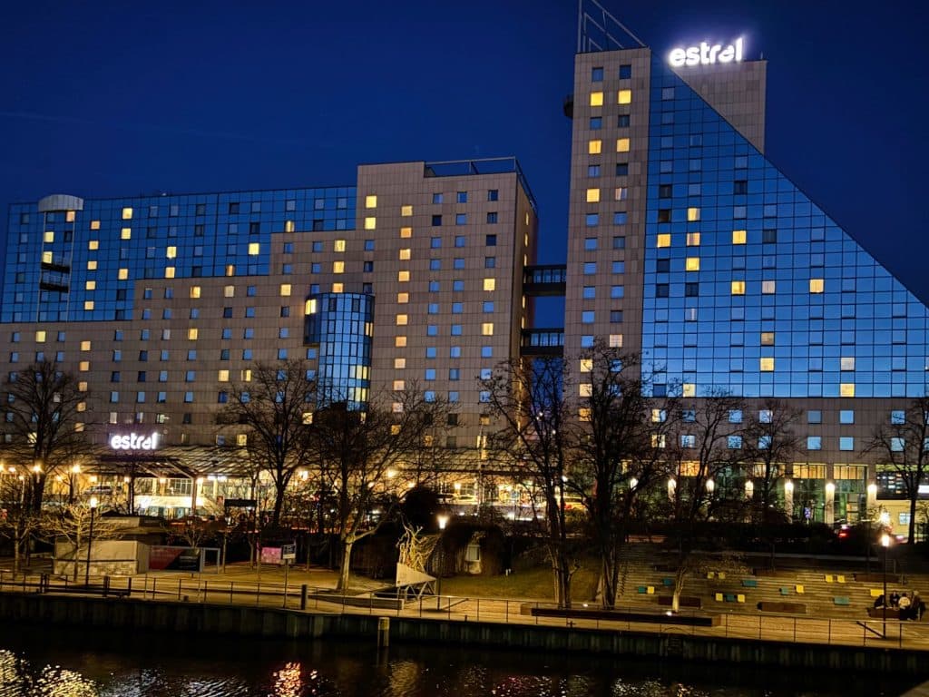 Abendliche Außenansicht des Estrel Berlin Hotels mit beleuchteten Fenstern und dem „estrel“-Schriftzug