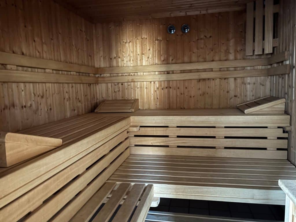 Innenansicht einer hölzernen Sauna im Hotel Hegenbarth's mit mehrstufigen Sitzbänken, hölzernen Kopfstützen und zwei Messgeräten an der Wand.