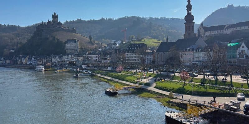 Blick auf die Stadt Cochem an der Mosel mit der Reichsburg auf einem Hügel im Hintergrund und der markanten St. Martin Kirche am Flussufer.