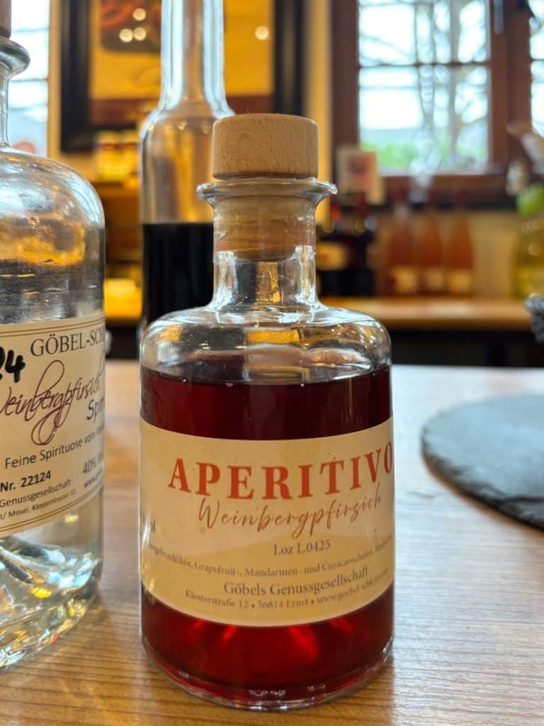 Eine Nahaufnahme einer kleinen Glasflasche mit rötlichem Weinbergpfirsich-Aperitivo der Göbels Genussgesellschaft.