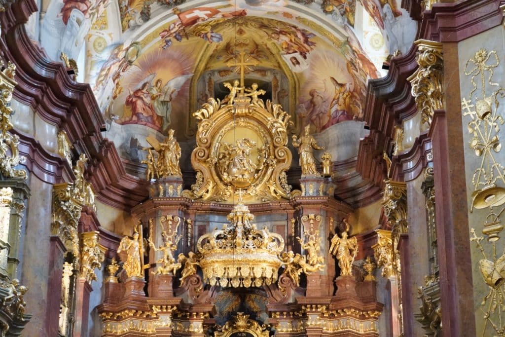 Detailansicht des prunkvollen, goldverzierten Hochaltars in der Stiftskirche von Melk mit zahlreichen Engelsfiguren vor einem farbenprächtigen Deckenfresko.