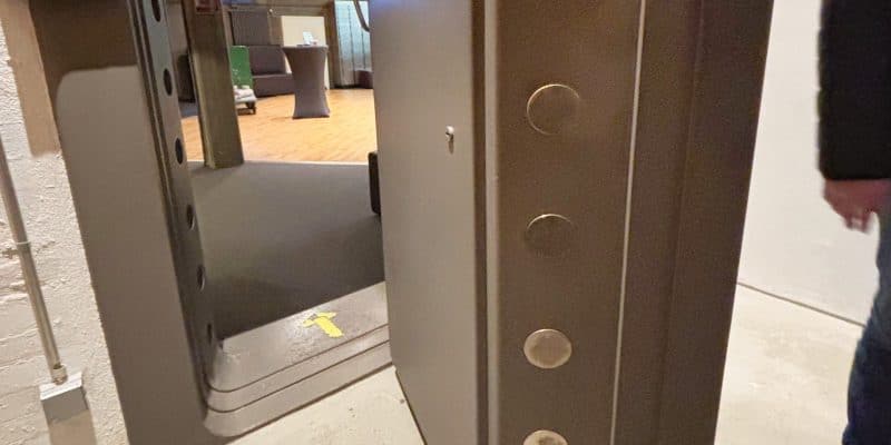 Eine massive, geöffnete Stahltür mit runden Verriegelungsbolzen gibt den Blick in einen hell erleuchteten Raum im ehemaligen Bundesbank-Bunker in Cochem frei.