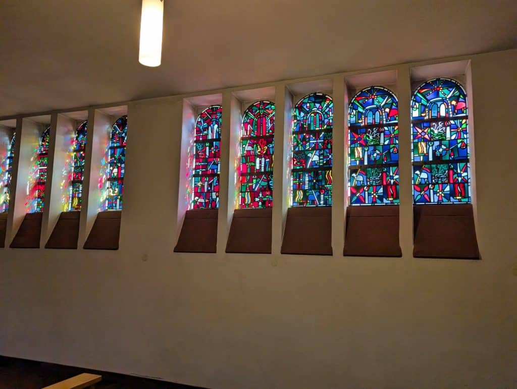 Bunte, moderne Buntglasfenster in einer Kirche in Cochem werfen farbenfrohe Lichtreflexe an die weißen Innenwände und die tiefen Fensternischen.