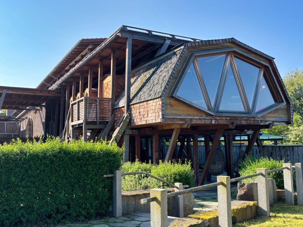 Ein moderner, hölzerner Anbau mit großen Panoramafenstern und Schindelfassade ergänzt die historische Architektur des Gradierwerks in der Therme Bad Sassendorf.