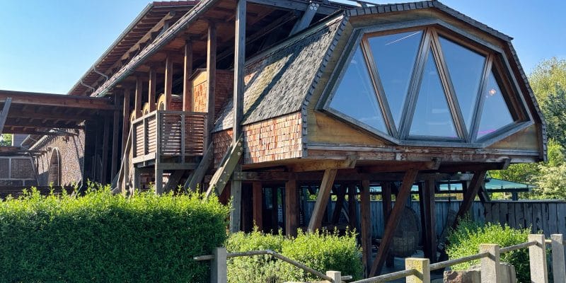 Ein moderner, hölzerner Anbau mit großen Panoramafenstern und Schindelfassade ergänzt die historische Architektur des Gradierwerks in der Therme Bad Sassendorf.