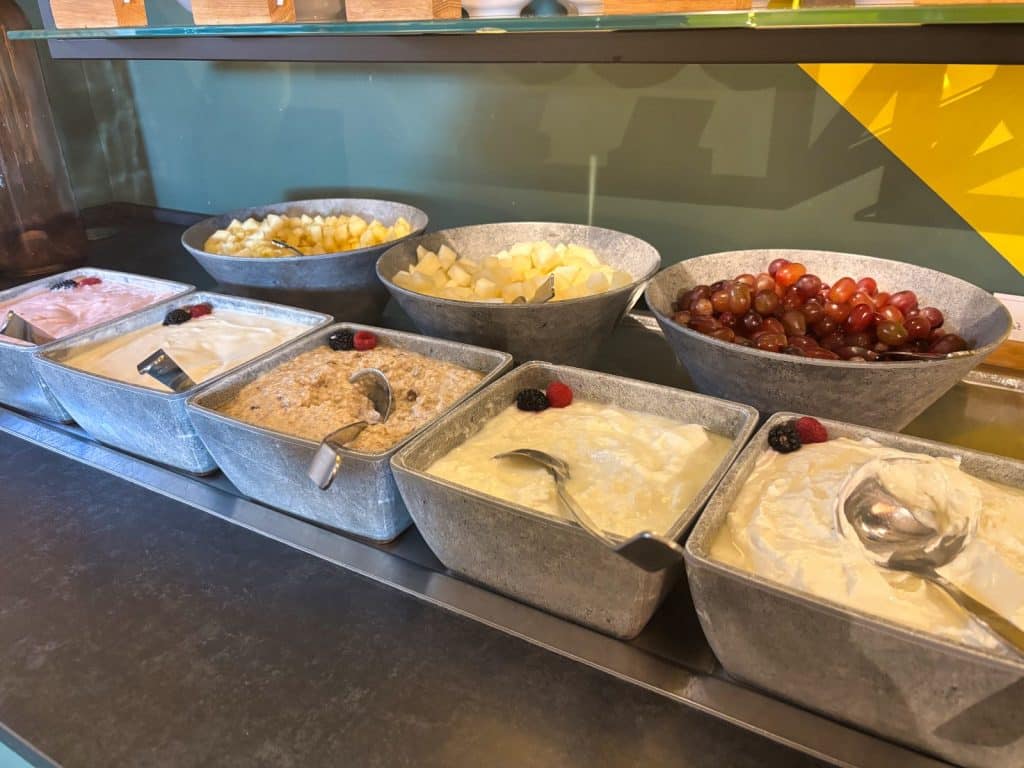 Ein reichhaltiges Frühstücksbuffet in Bad Sassendorf mit verschiedenen Schalen, die Müsli, Joghurt, Quark und frisches Obst wie Weintrauben, Melonenstücke und Beeren enthalten.