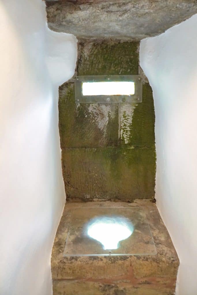 Eine historische Steintoilette in der Stadtmauer von Soest, bestehend aus einer gemauerten Nische mit einer runden Bodenöffnung und einem schmalen Lichtschlitz in der Außenwand.